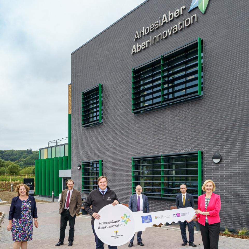 A group of people holding a giant key standing outside the Aberystwyth Innovation and Enterprise Campus