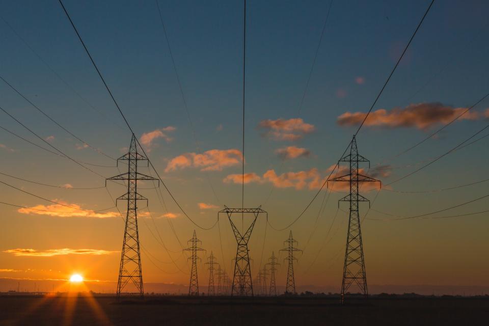 electricity pylons against a sunset