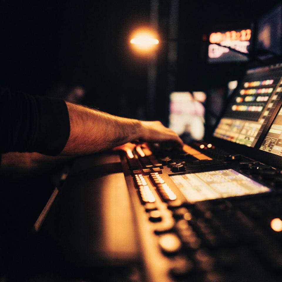 A close up of someone's hands operating a mixing desk