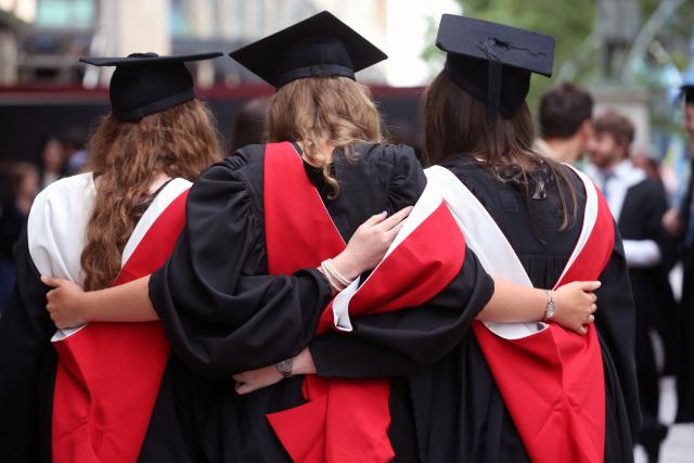 3 females wearing graduation cap and gowns with their backs to the camera