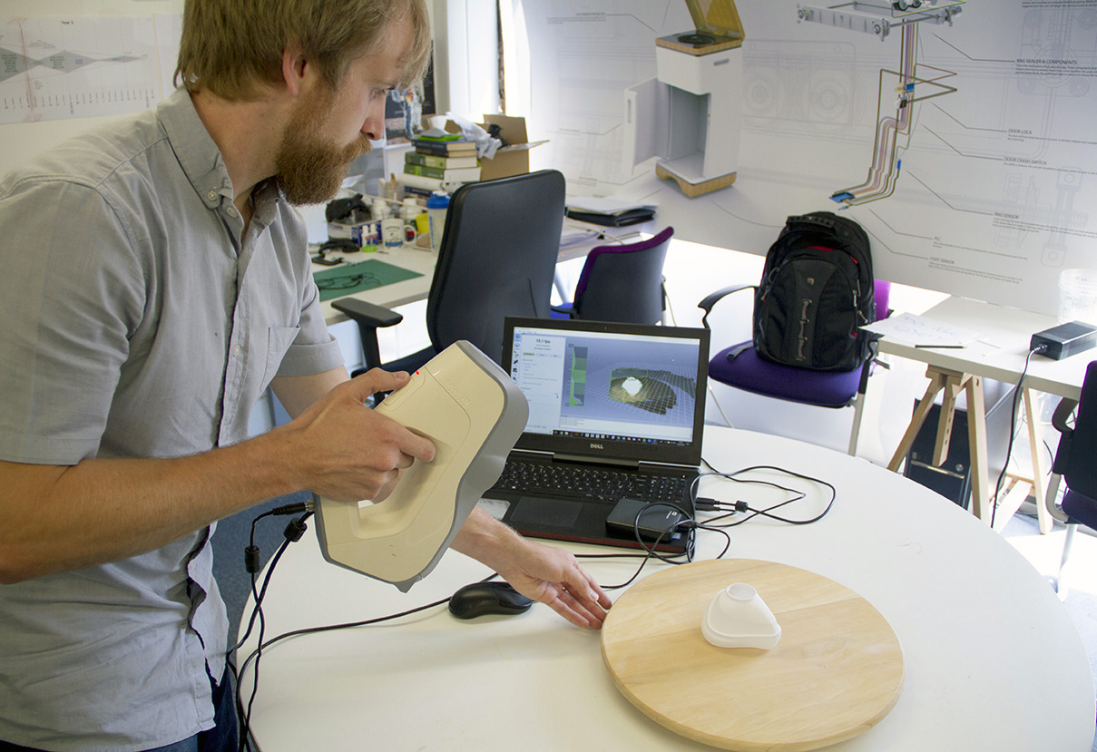 A man using a hand-held scanner and laptop