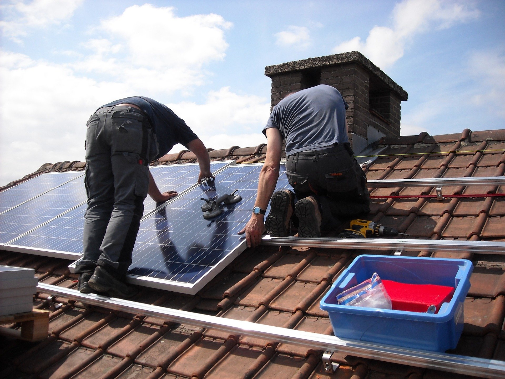 two men fitting solar panels on a roof