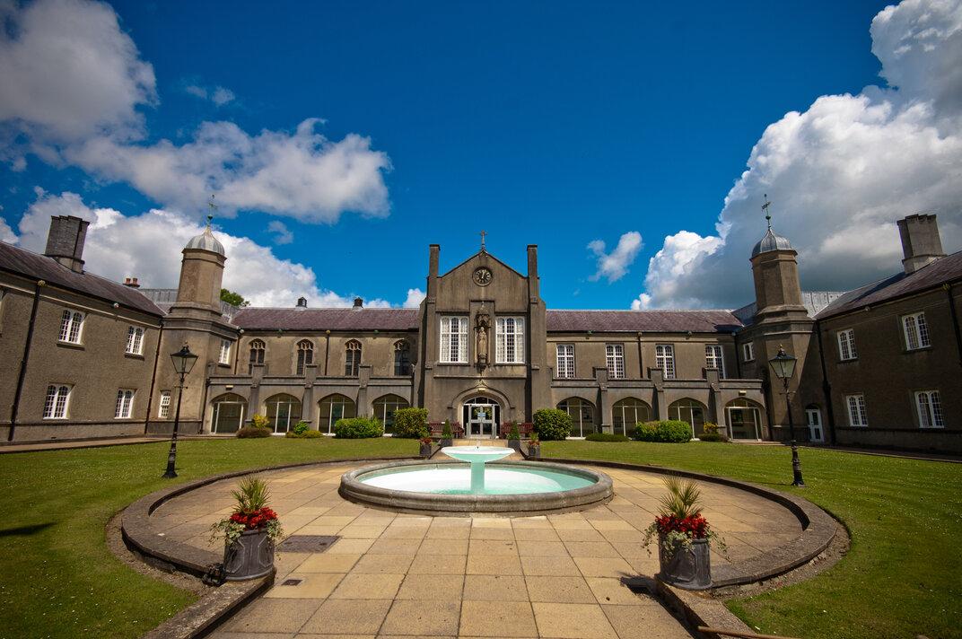 Large stone building with a lawn, paving slabs and a fountain