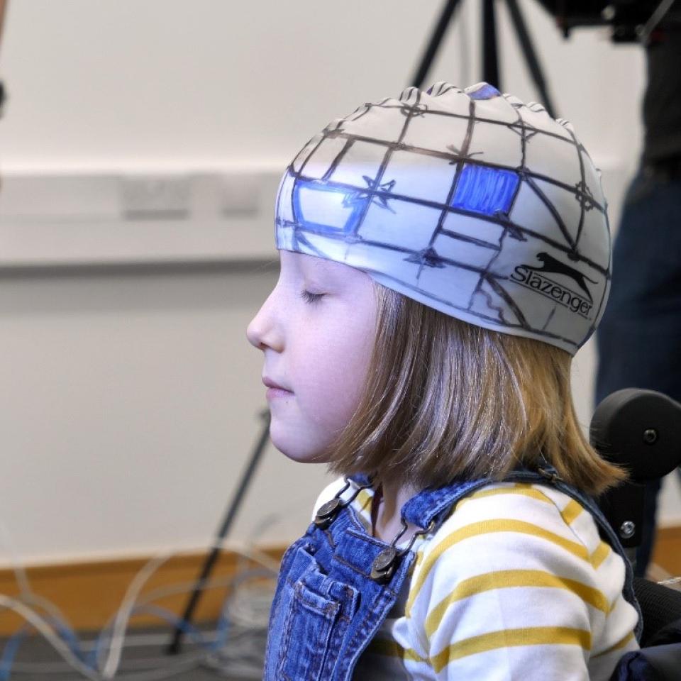 A young girl wearing a cap with sensors