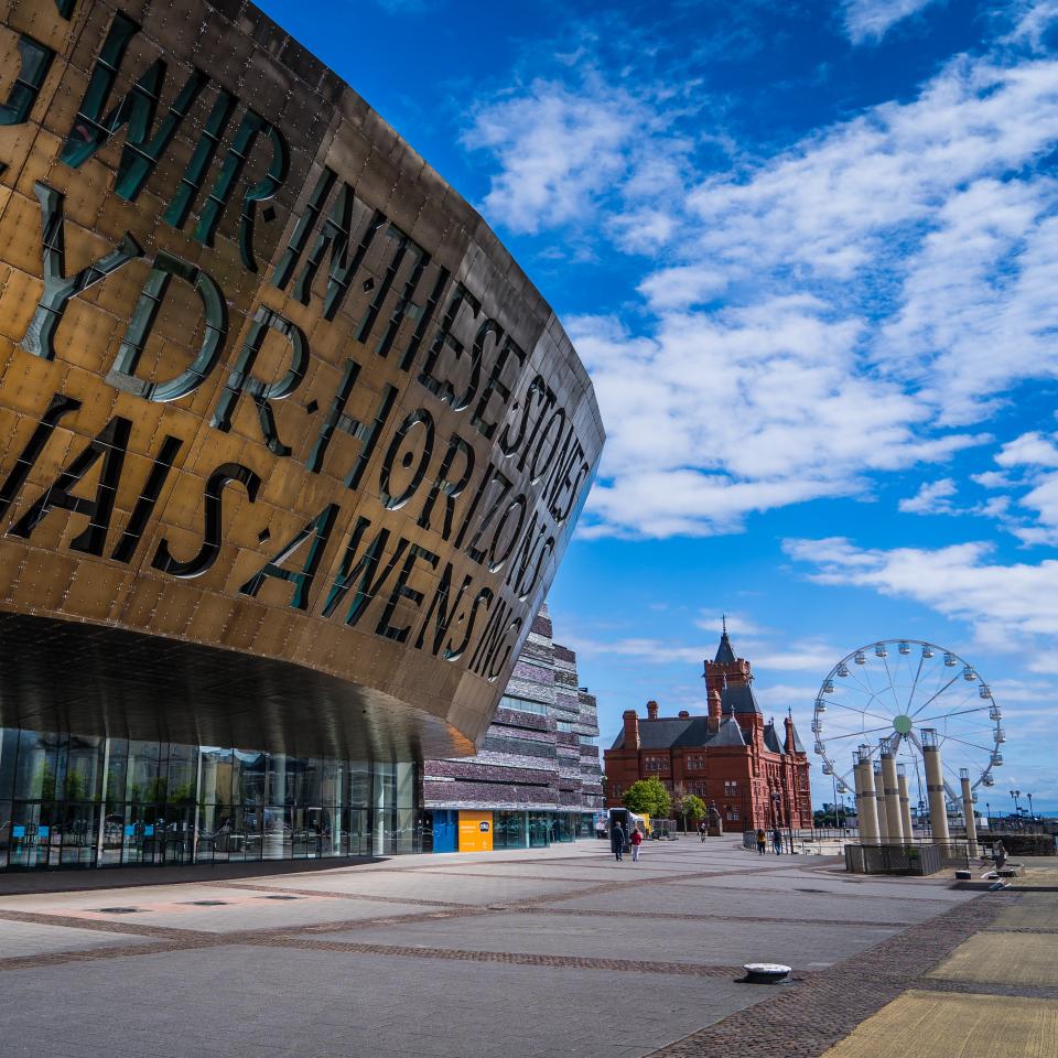A close up of Wales Millennium Centre with a ferris wheel and Pierhead Building in the background