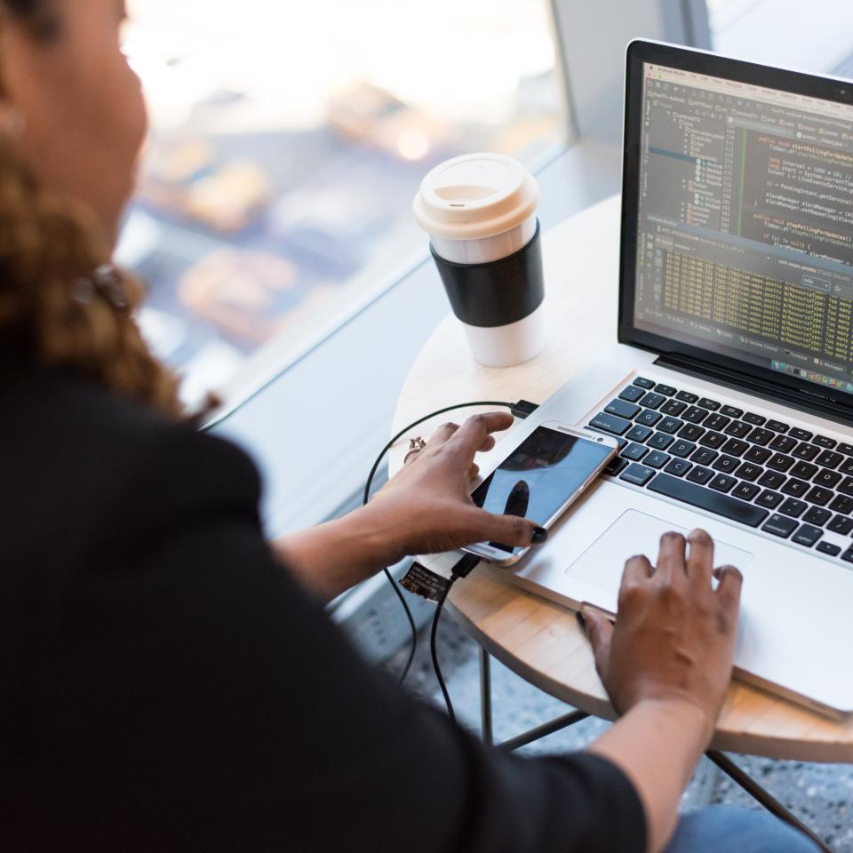 A woman sat at a small round table working on a laptop