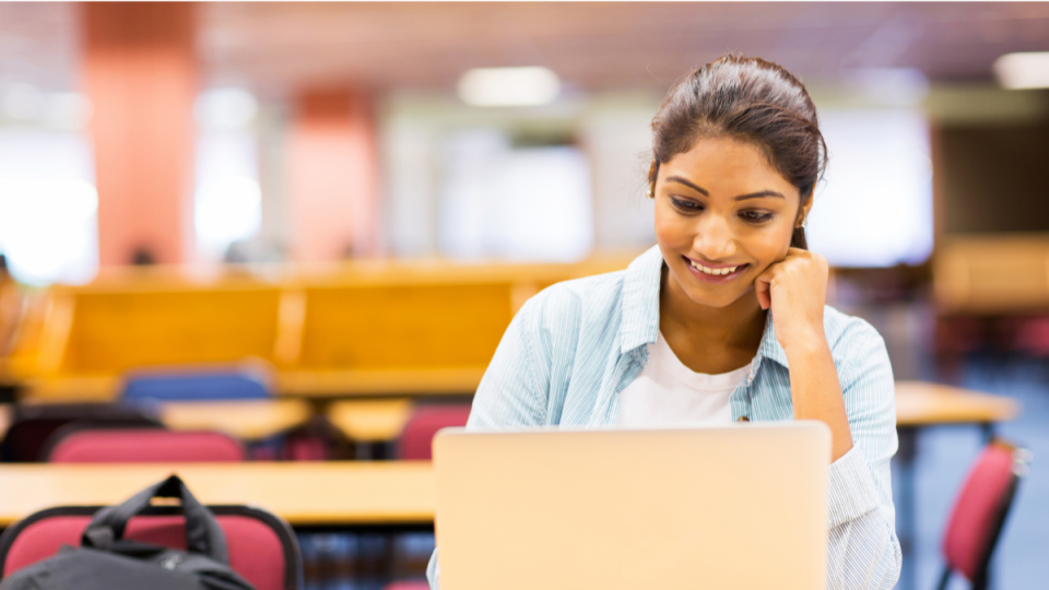 female student working on a laptop in a library