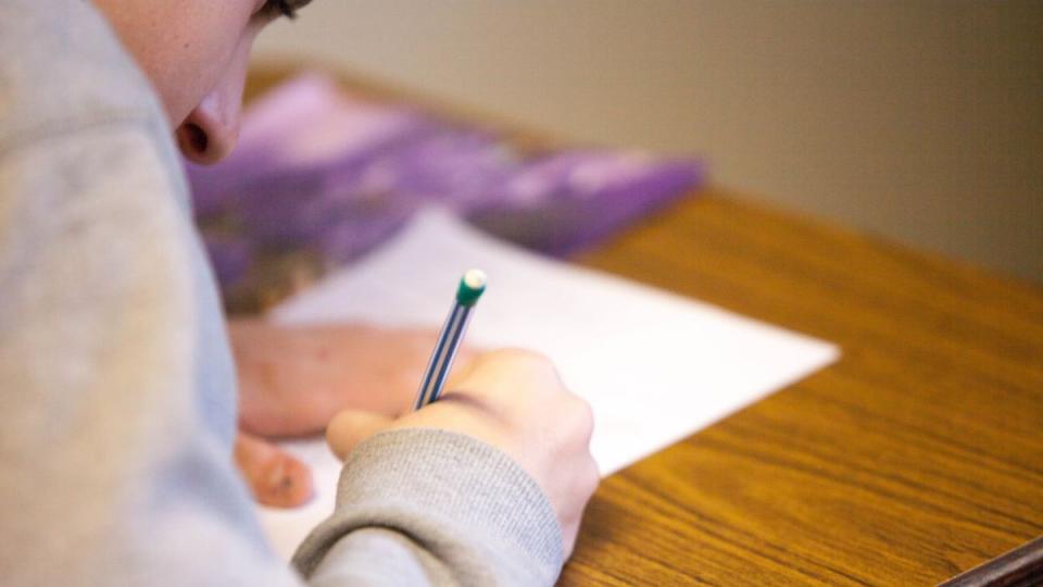 Person writing on a piece of paper on a desk