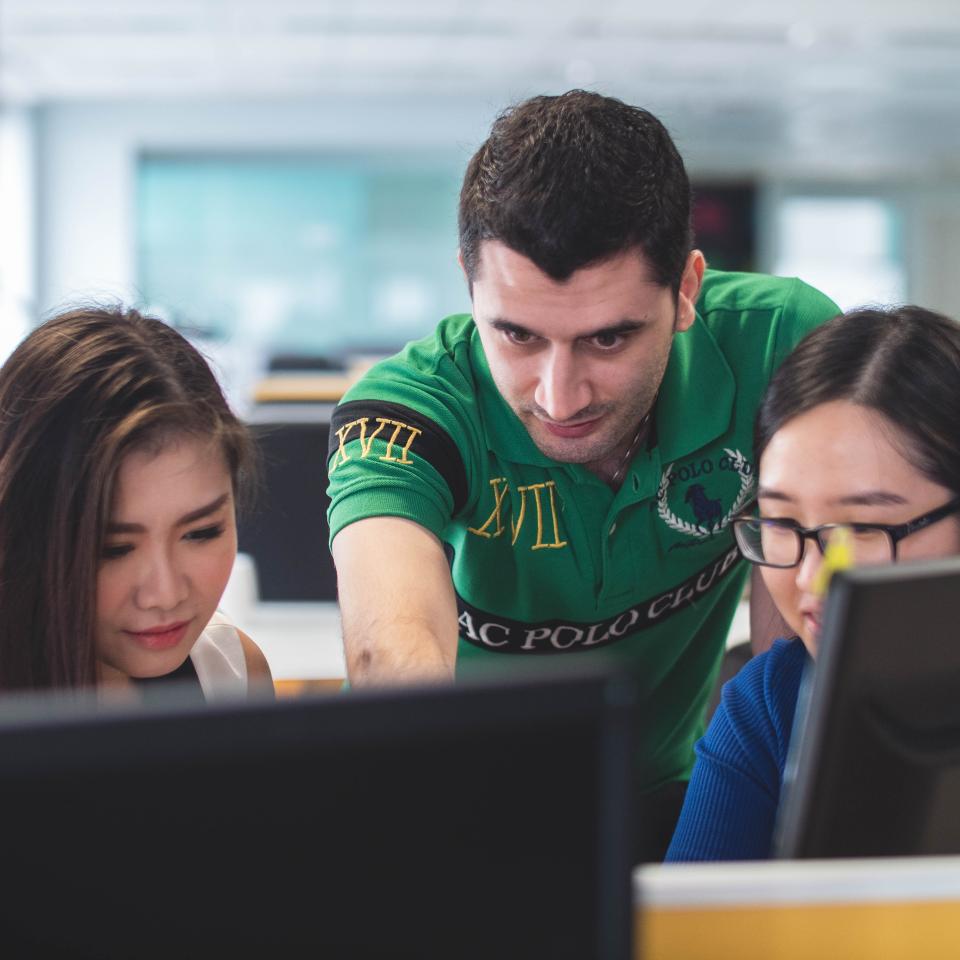 Two female students and a male teacher working on computers