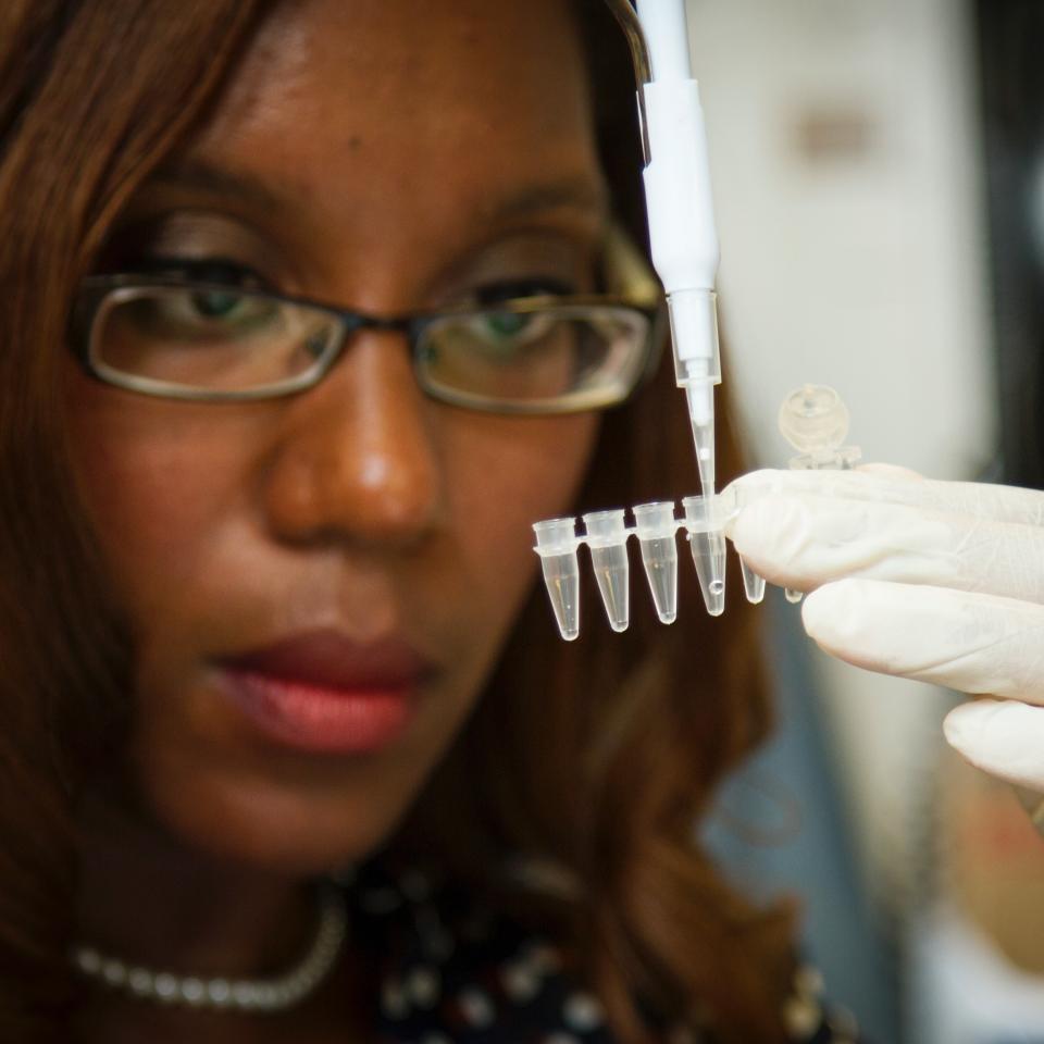 A female scientist pipetting samples into a tube