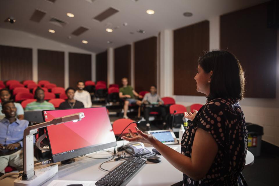 Woman presenting to a people in a lecture theatre