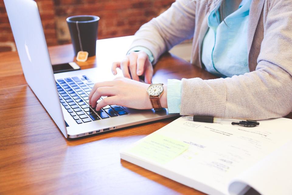 Woman working on a laptop with a cup of tea next to her