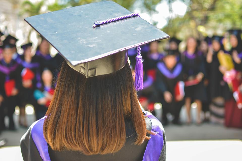 Female graduate looking out at a crowd of graduating students