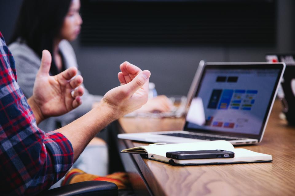 People sat around a meeting table with laptops