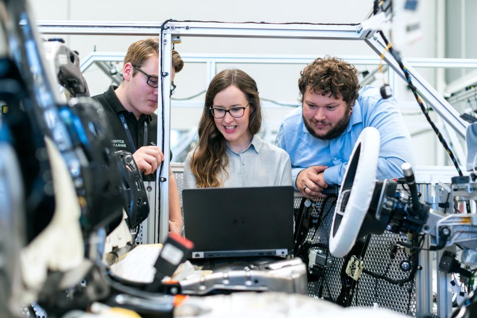 Three engineers working together on a car