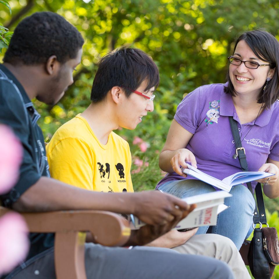 Three students sat on a bench, talking to each other