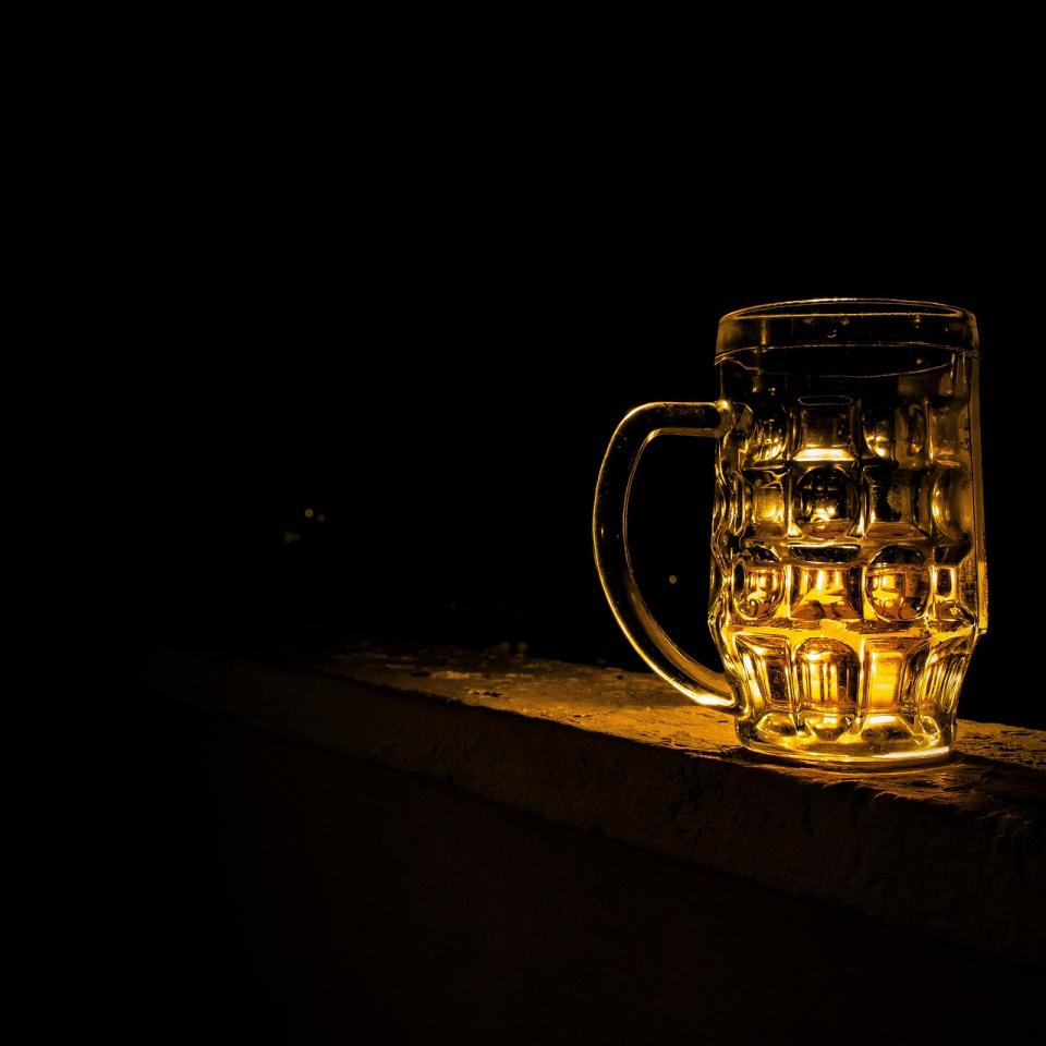 A lit-up pint glass against a dark background