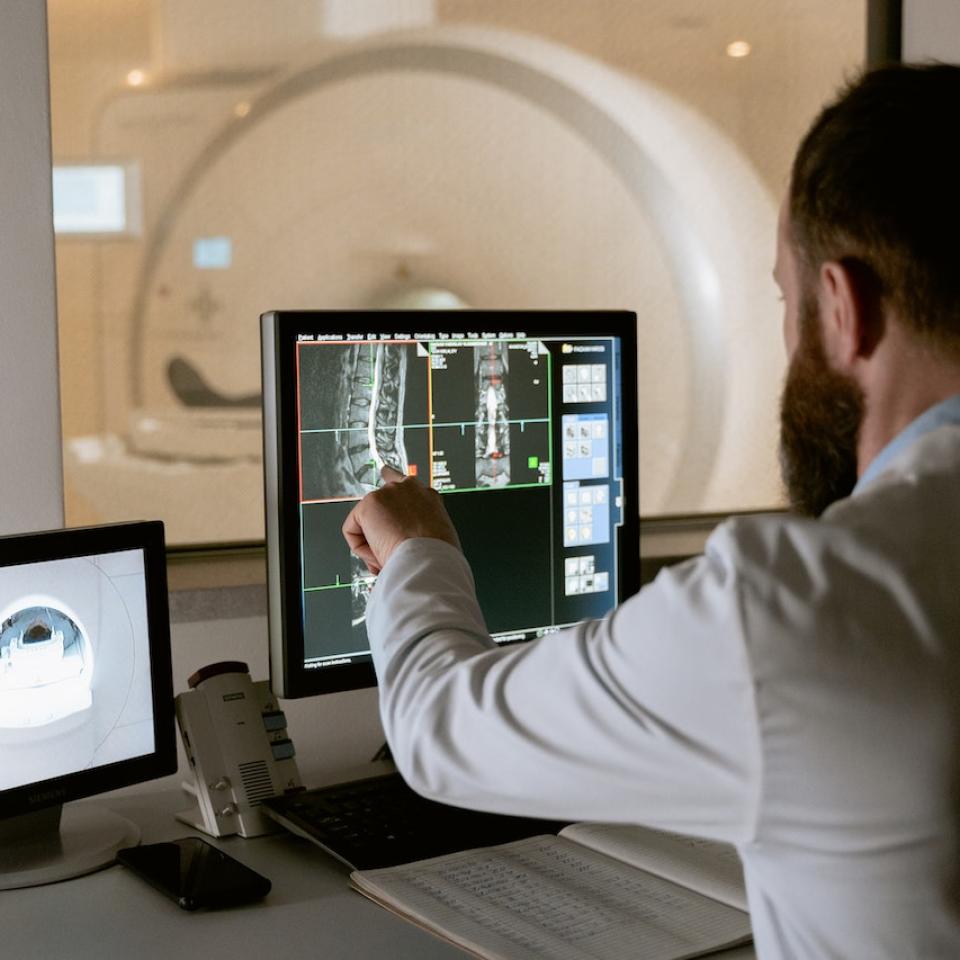 A man in a white coat looking at MRI images