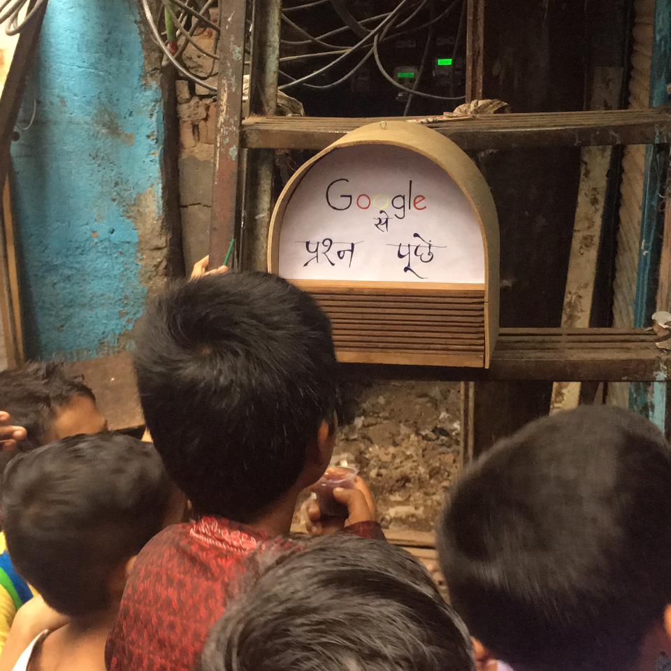 Children looking at a prototype of a smart speaker in India