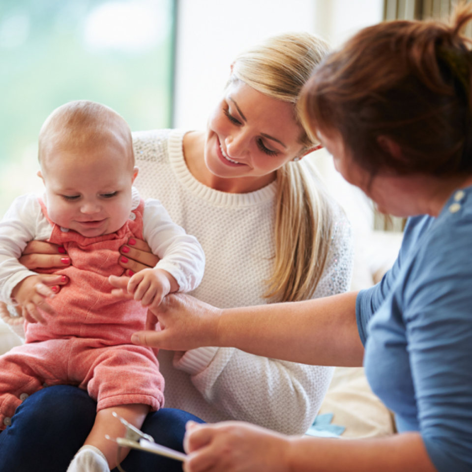 A female health visitor with a mother and her baby