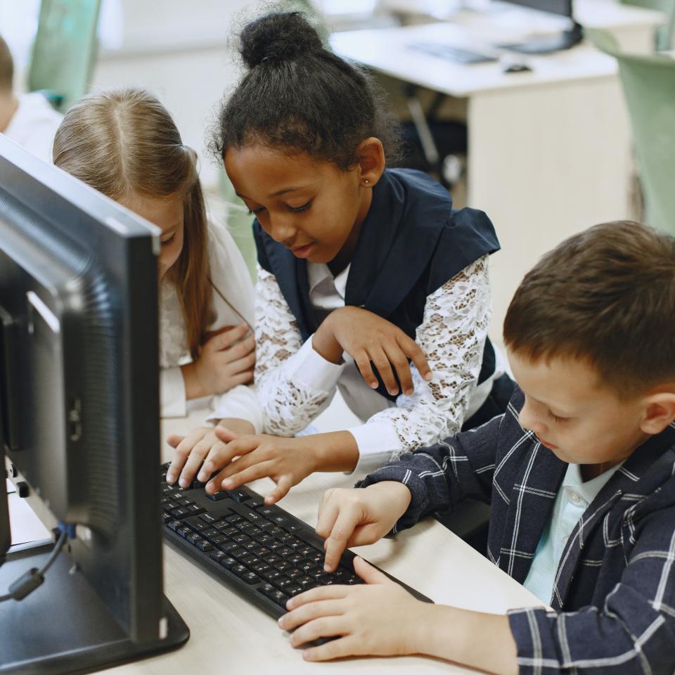 3 young children gathered around a computer