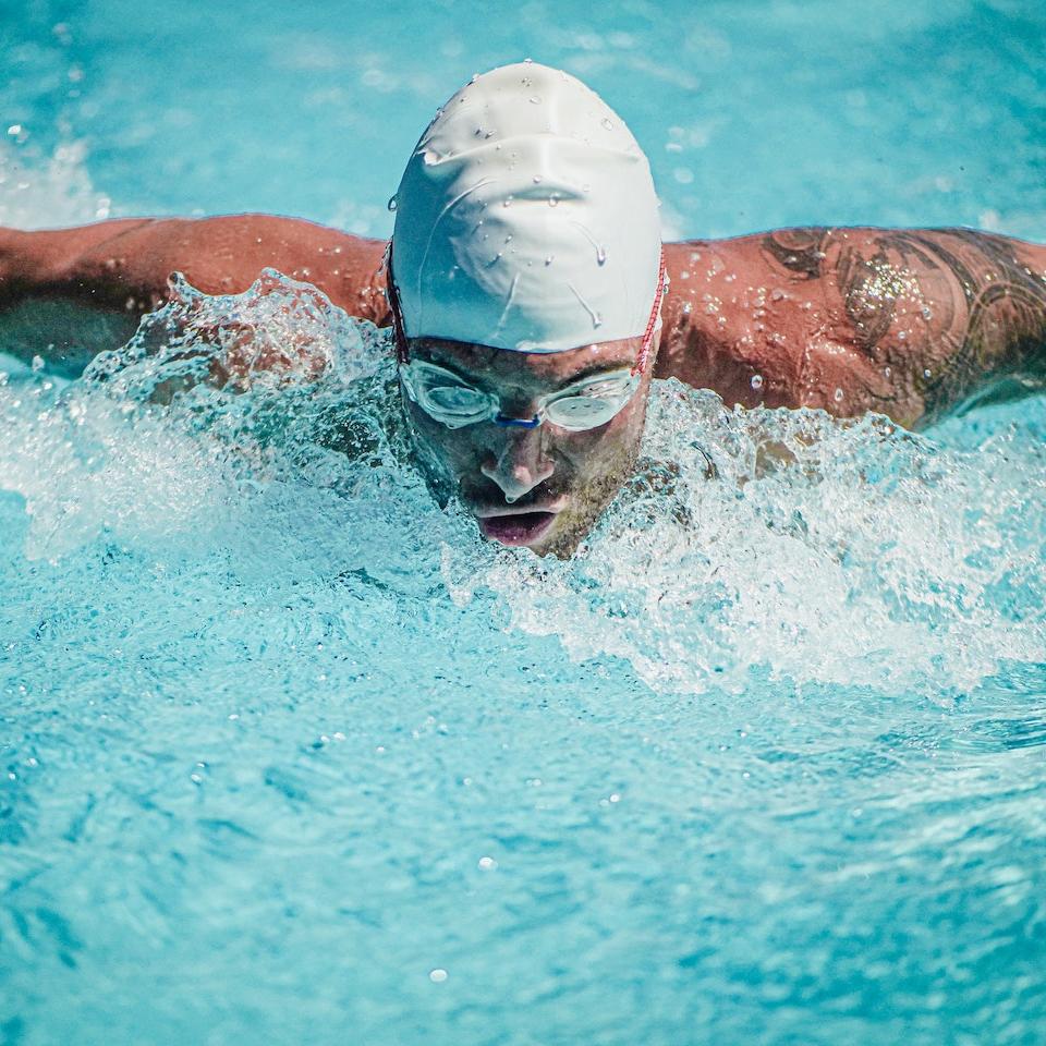 Close up shot of a man swimming butterfly in a pool