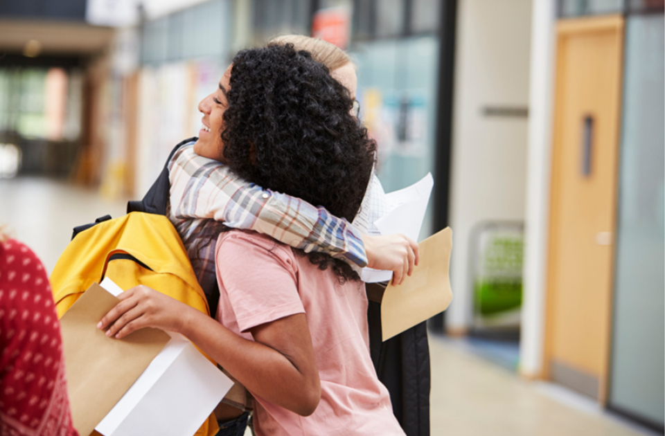 2 female students hugging and holding exam results