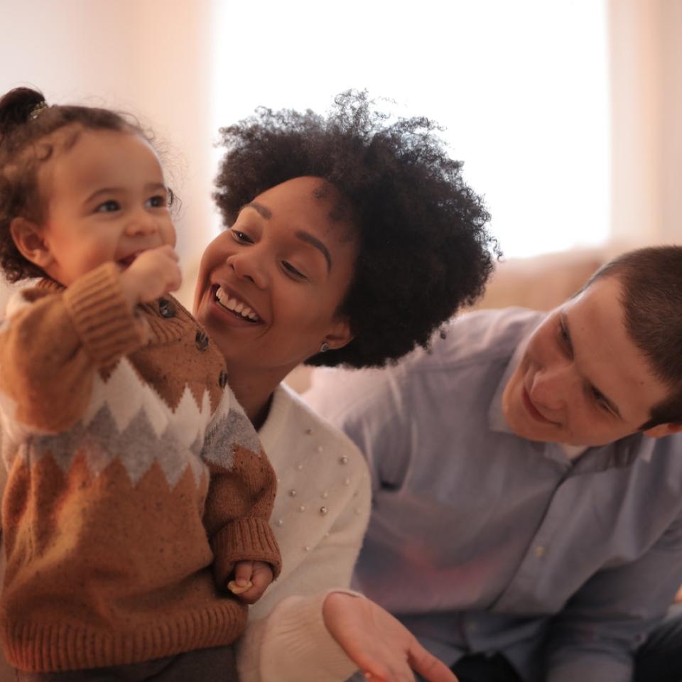 A mother and father playing with their young child