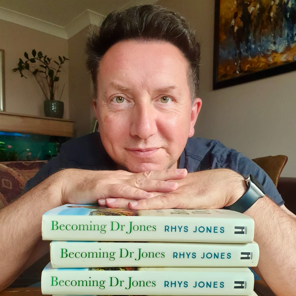 Rhys Jones with a pile of books that he authored