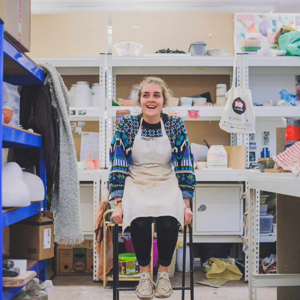 Smiling woman wearing in an apron sitting in a workshop