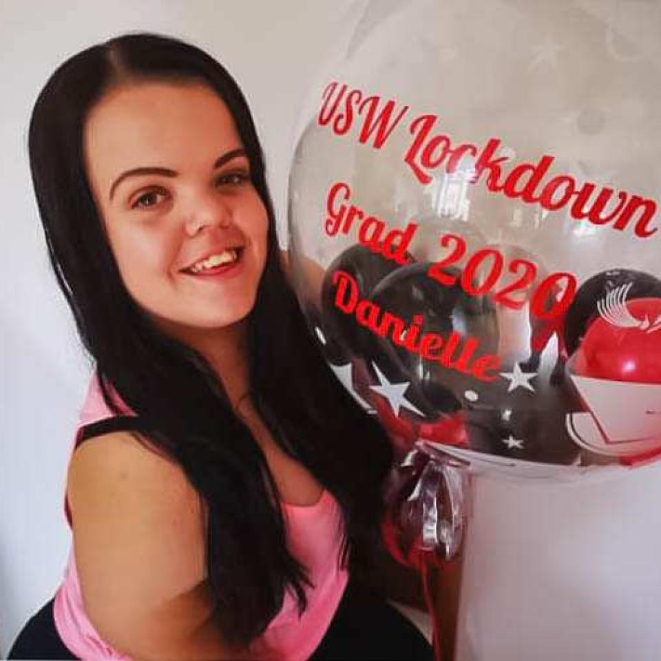 Photo of Danielle holding a graduation balloon