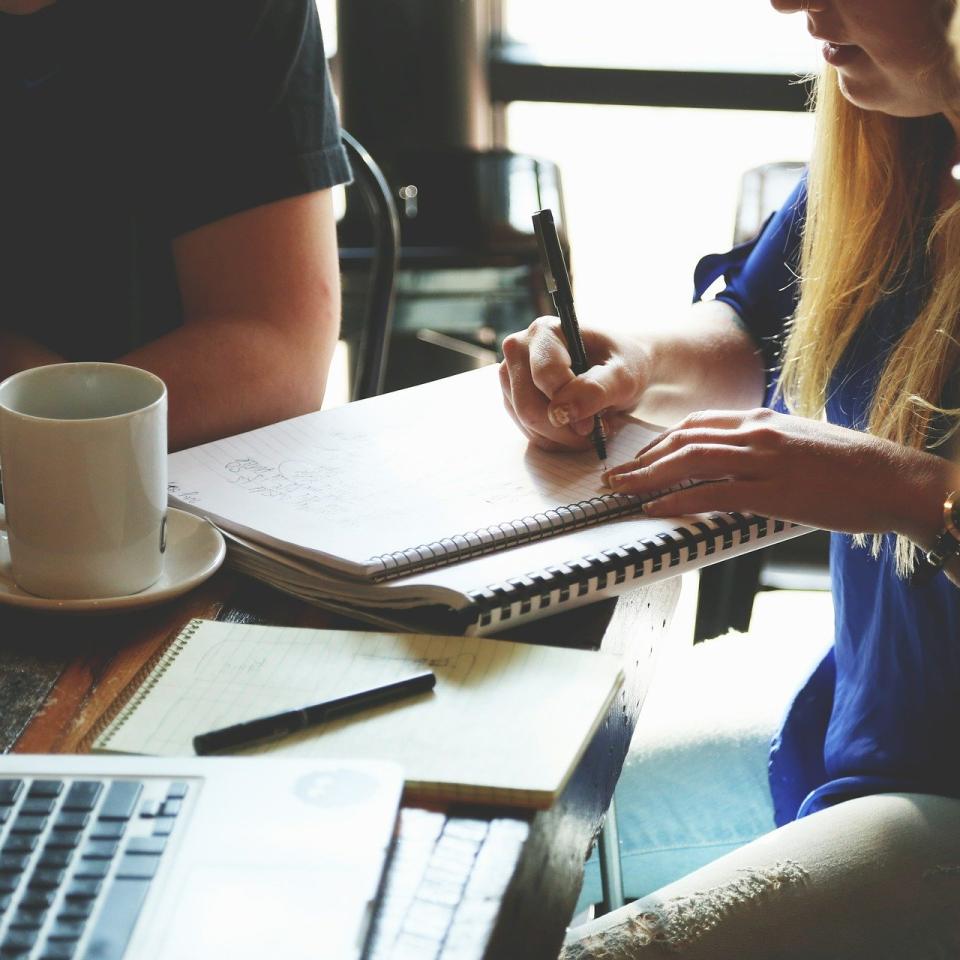 A group of people sitting around a table with laptops and notepads