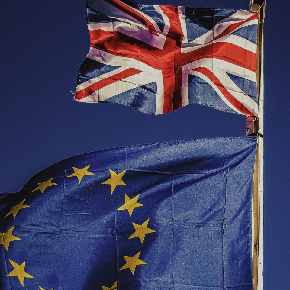 UK flag and EU flag against a blue sky