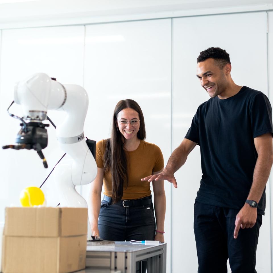 A man and woman standing by a robotic piece of machinery