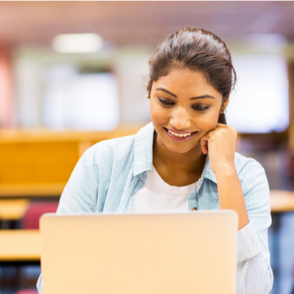 Student smiling looking at a laptop screen