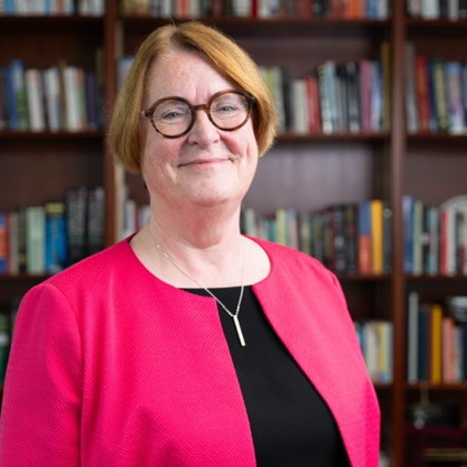 Professor Elwen Evans, KC, standing in front of book shelves
