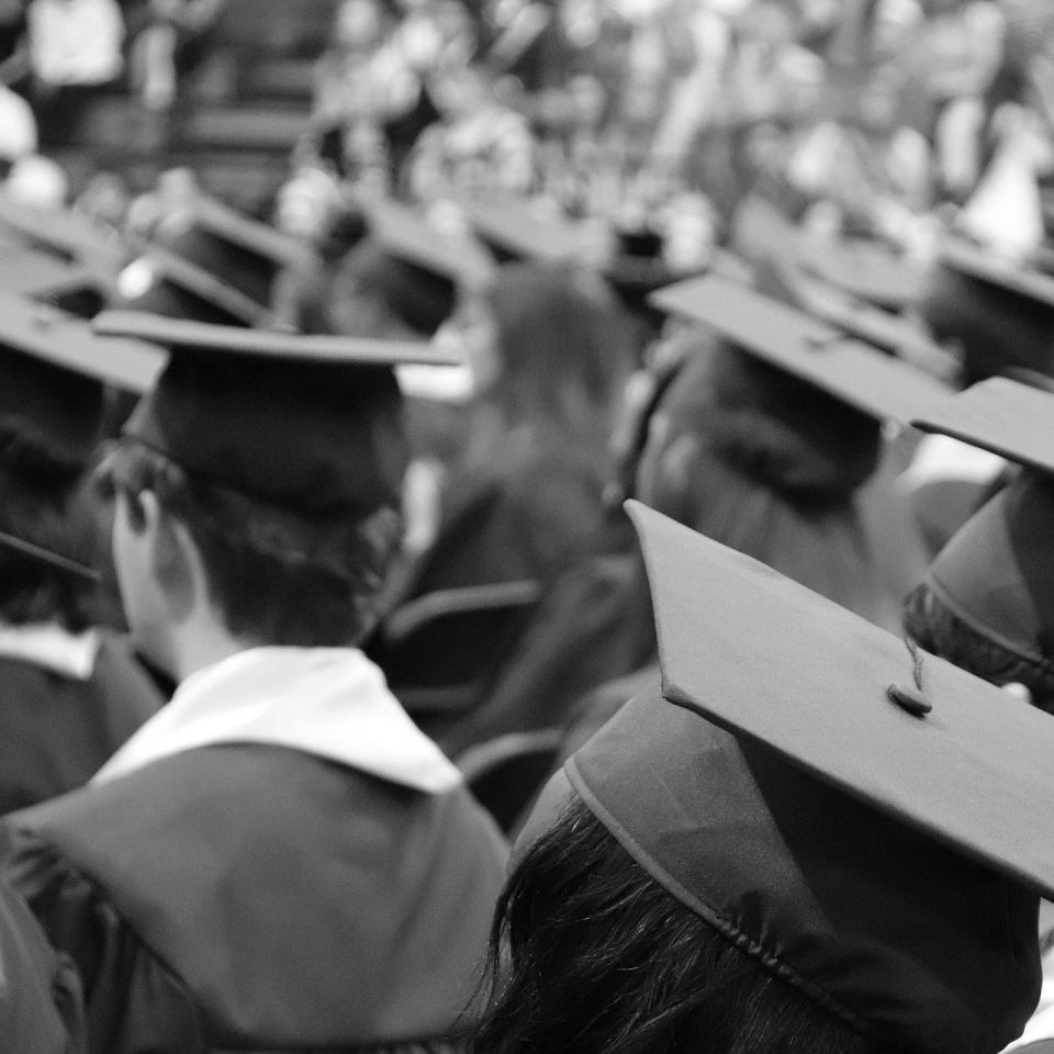 Black and white image of crowd of people in graduation robes