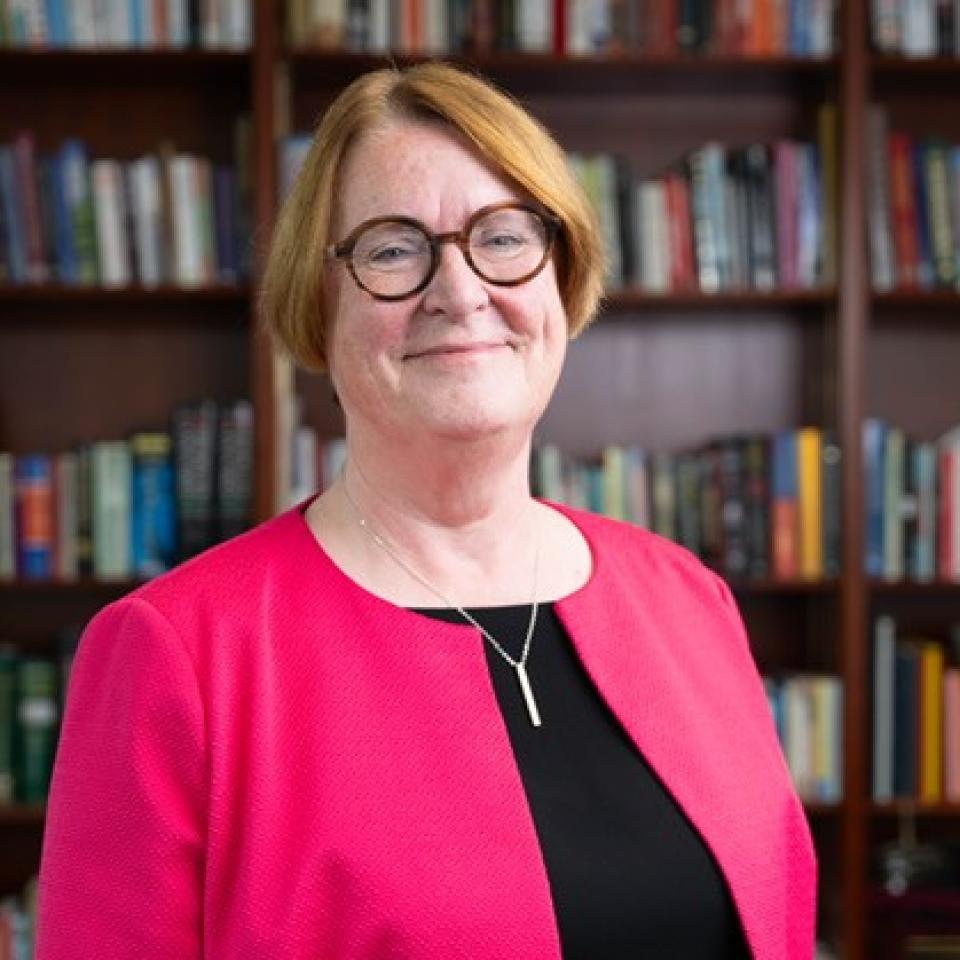 A photo of Professor Elwen Evans standing in front of bookshelves