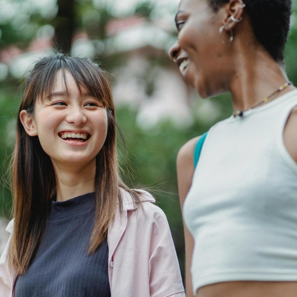 Two women walking outdoors smiling and talking to each other