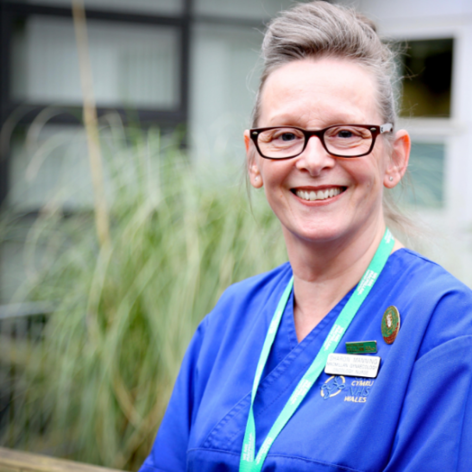 A photo of Sharon smiling and wearing nursing scrubs