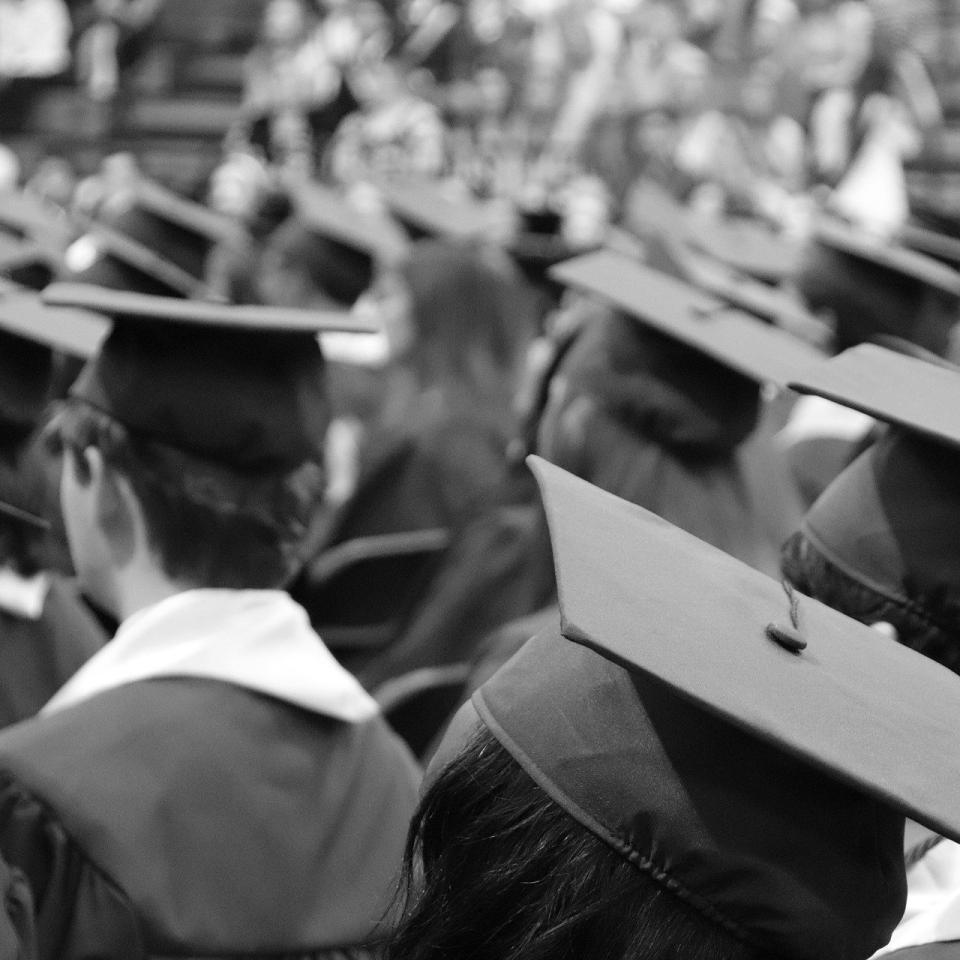 A black and white photo of a crowd of people in graduation robes