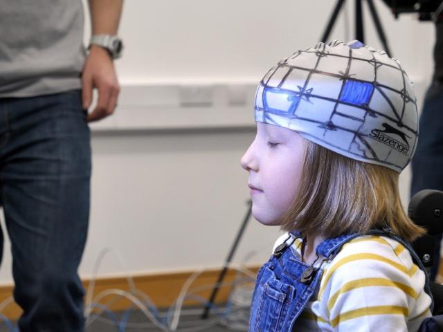 A young girl wearing a cap with sensors