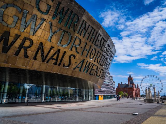 A close up of Wales Millennium Centre with a ferris wheel and Pierhead Building in the background