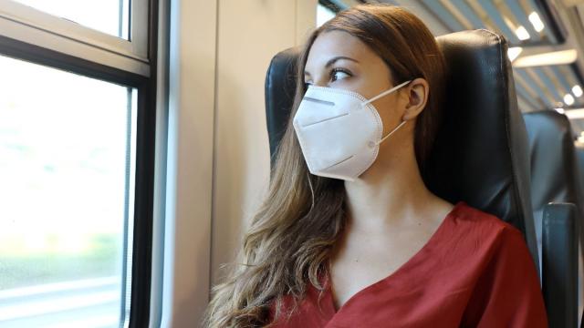 Young woman traveling on a train wearing a face mask