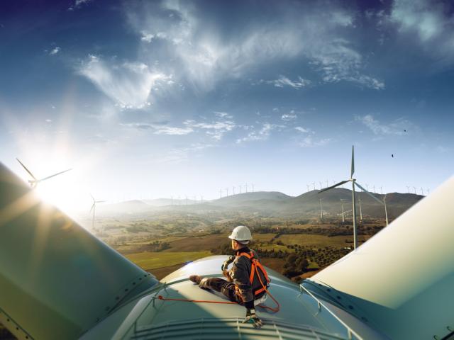 Man sitting on a wind turbine looking over the countryside