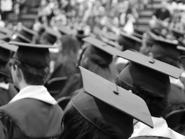 A black and white photo of lots of people in graduate caps and gowns