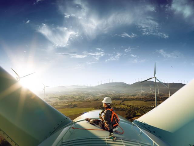 Engineer sitting on a wind turbine with views over mountains