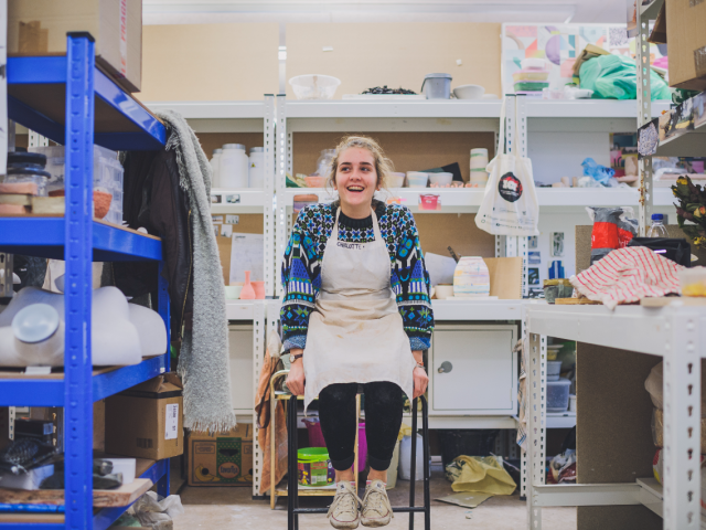 Smiling woman wearing in an apron sitting in a workshop