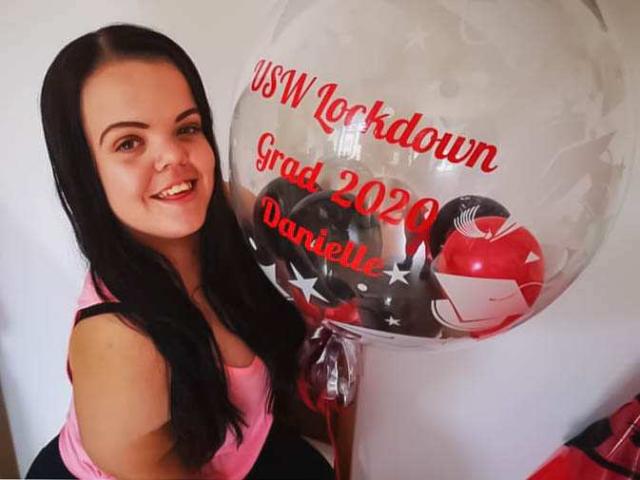 Photo of Danielle holding a graduation balloon