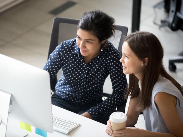 Two women working at a desktop computer